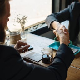 man and woman shaking hands over business dinner